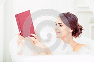 Beautiful young woman in bath with a book