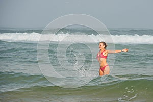 beautiful young woman bathing in the ocean in bikini