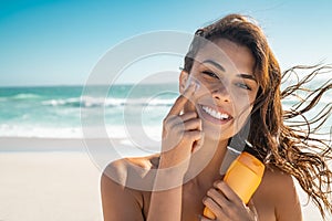 Smiling woman applying sunscreen photo