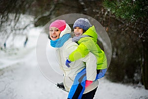 Beautiful young woman bears on the son`s shoulders through snowdrifts.