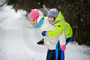 Beautiful young woman bears on the son`s shoulders through snowdrifts.