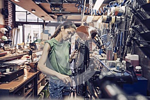 A beautiful young woman bicycle mechanic is repairing a bike in the workshop