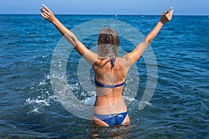 Beautiful young woman in bikini on the beach splashing water - Image. Incredible Santorini - Greece