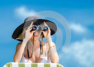 Beautiful young woman in bikini looking through binoculars