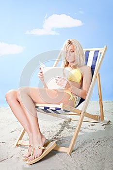 Beautiful young woman in bikini reading a book