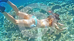 Beautiful young woman in bikini snorkeling with diving mask whowing Gesture two fingers up and waving at the camera