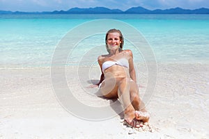 Beautiful young woman in bikini on the sunny tropical beach relaxing