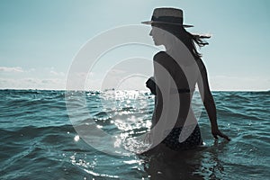 Beautiful young woman in bikini on the sunny tropical beach relaxing in water