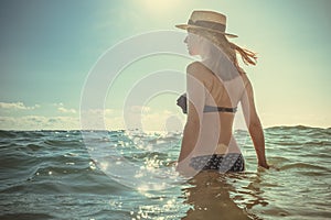 Beautiful young woman in bikini on the sunny tropical beach relaxing in water