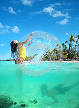 Beautiful young woman in bikini on the sunny tropical beach relaxing in water