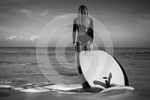 Beautiful young woman in bikini with surf board at beach of tropical island.