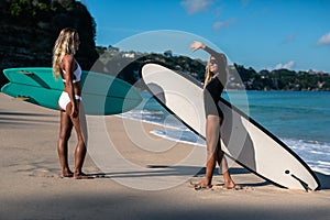 Beautiful young woman in bikini with surf board at beach of tropical island.