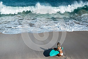 Beautiful young woman in bikini with surf board at beach of tropical island.