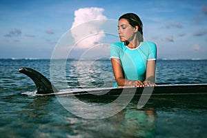 Beautiful young woman in bikini with surf board at beach of tropical island.