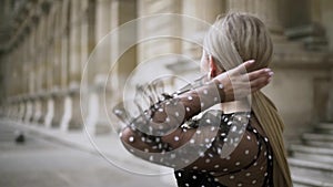 Beautiful young woman in a black chiffon dotted dress looking provocatively and touching her hair. Action. Sexy blond