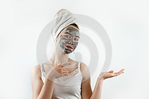 Beautiful young woman with black clay facial mask for perfect fresh clean skin isolated on white