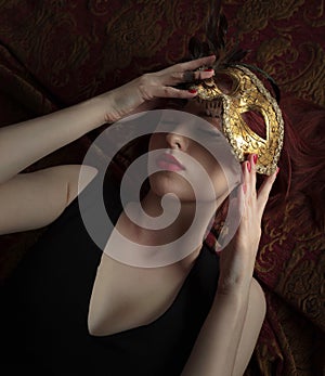 Beautiful young woman in black dress with carnival mask.