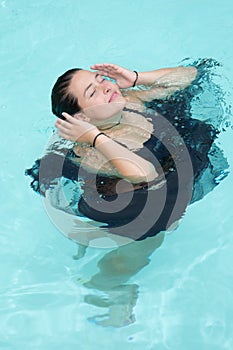 Beautiful young woman in black dress girl swimming in swimming pool