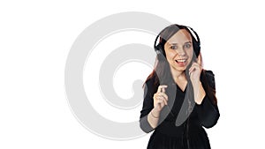 A beautiful young woman in a black dress and in headphones is smiling on isolated white background. Copy space.