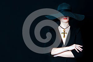 Beautiful young woman in black hat with jewel cross