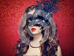 Beautiful young woman in black mysterious Venetian mask
