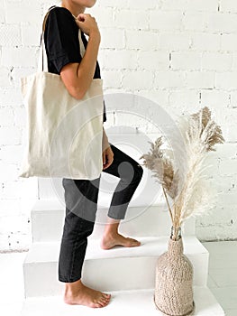 Beautiful young woman in black t-shirt and jeans holding a tote bag or shopper