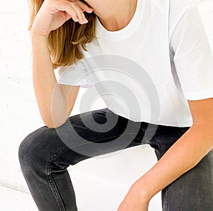 Beautiful young woman in blank white t-shirt and black jeans sitting on the stairs