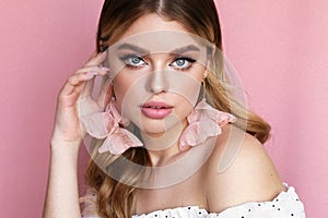 Beautiful young woman with blond natural hair and light makeup posing at studio