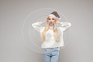 Beautiful young woman with blonde hair poses on camera tpuches her hair and screams, picture isolated on white