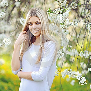 Beautiful young woman in blooming tree in spring