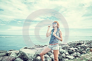 Beautiful young woman blowing bubble in outdoor, nature, near the ocean. Tropical magic island Bali, Indonesia.