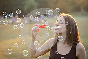 Beautiful Young Woman Blowing Bubbles Outside