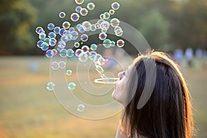 Beautiful Young Woman Blowing Bubbles Outside