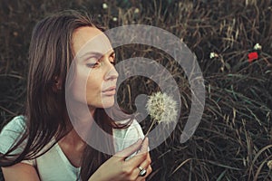 Beautiful Young Woman blowing on dandelion