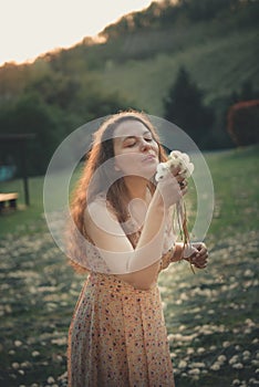 Beautiful young woman blowing a dandelion