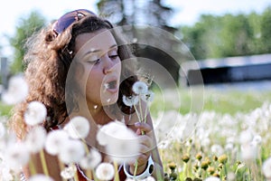 Beautiful young woman blowing a dandelion