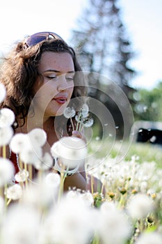 Beautiful young woman blowing a dandelion