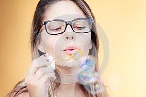 Beautiful young woman blowing soap bubbles outdoors