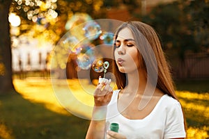 Beautiful young woman blowing soap bubbles in the park