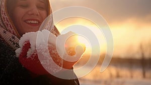 Beautiful young woman blows snowflakes and smiling in slow motion during sunset time with lens flare effects. 1920x1080