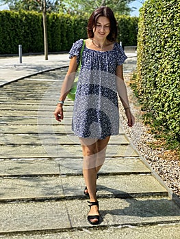 Beautiful young woman in blue dress walks through park in Krasnodar