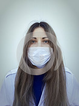 Beautiful young woman with blue eyes, wearing a white protective mask. White background