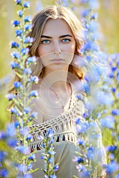 Beautiful young woman in blue flowers outdoors. Ã‰chium vulgÃ¡re. Boho style clothing. Selective DOF