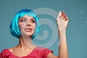 Beautiful young woman with blue wig and bright make-up in soap bubbles. Fashion model girl with creative color makeup