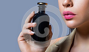 Beautiful young woman with bottle of perfume, closeup. Woman with bottle of perfume. Woman presents perfumes fragrance