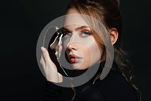 Beautiful young woman with broken mirror on black background