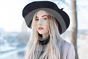 Beautiful young woman with brown eyes with lips with blond hair with beautiful make-up in an elegant black hat