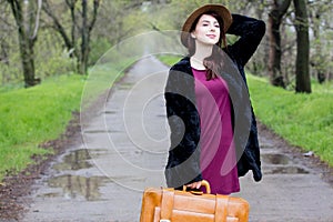 Beautiful young woman with brown suitcase standing in the middle
