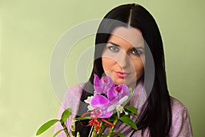The beautiful young woman the brunette with green eyes and a pink orchid.