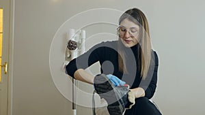 A beautiful young woman brushes her shoes before going to work. Shoe care at home